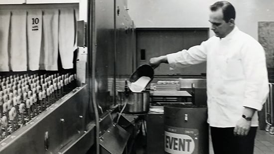 Black and white image of an Ecolab technician scooping a product into equipment