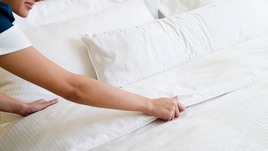 housekeeper making bed in a hotel room